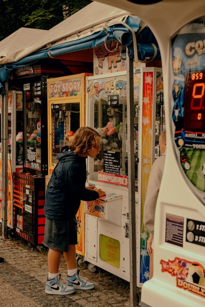 A child engaged with a claw machine at an outdoor arcade festival, enjoying a fun day.